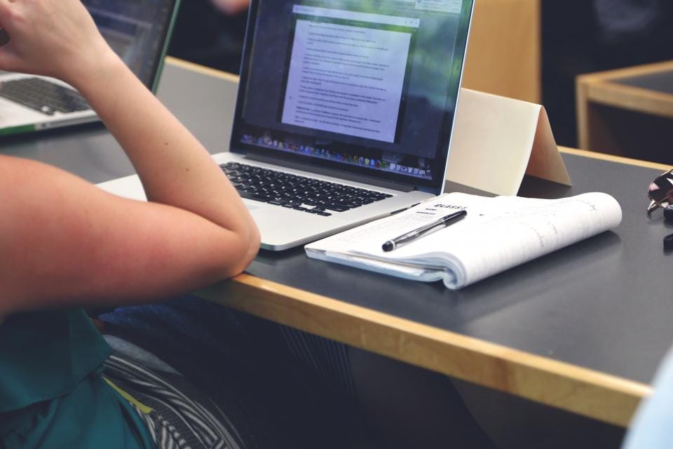 A trader at a desk with a laptop and a notepad, planning before the trade